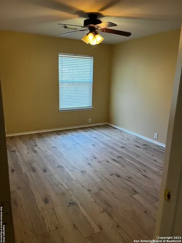 a view of an empty room with window and chandelier fan