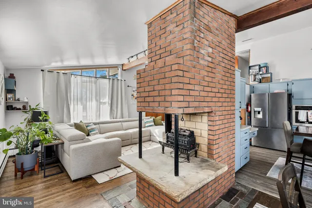 a living room with couches and a dining table with wooden floor