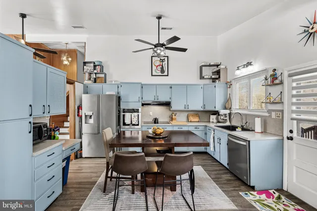 a kitchen with stainless steel appliances a stove a sink dishwasher and white cabinets with wooden floor