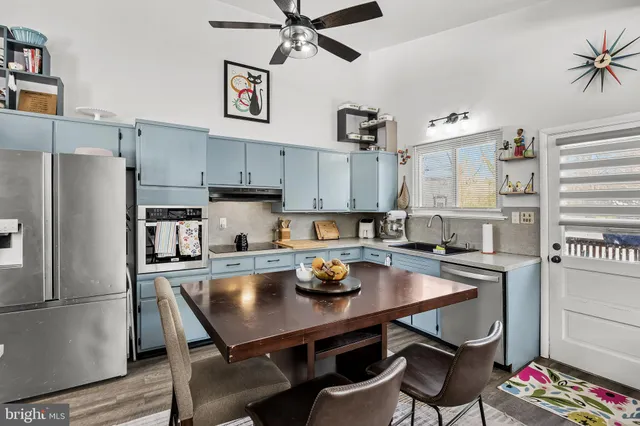 a kitchen with stainless steel appliances a table chairs and a refrigerator
