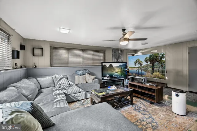 a living room with furniture a flat screen tv and a window