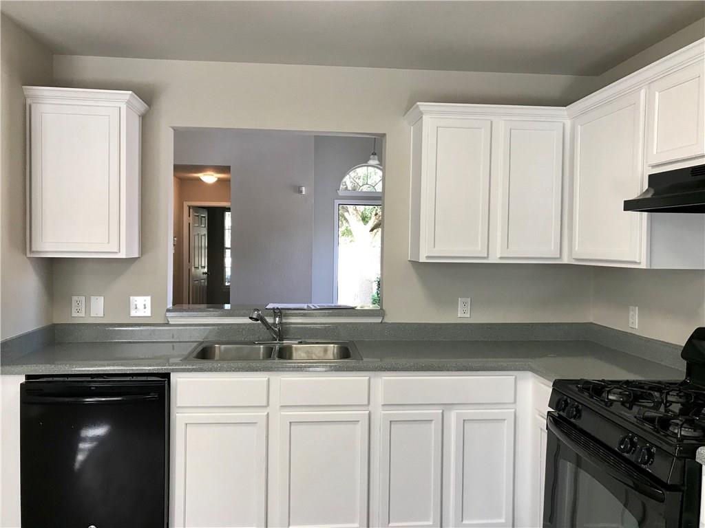 1251 Pine Portage Loop Leander, TX 78641 - Photo 6 of 17 a kitchen with granite countertop white cabinets and black appliances