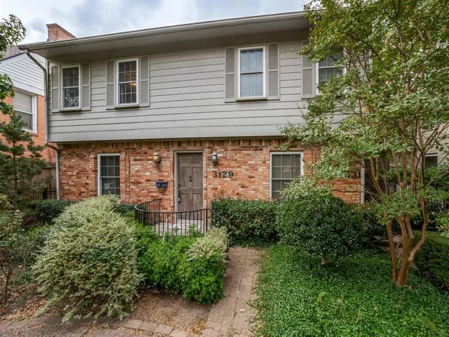 a view of a house with plants and large trees