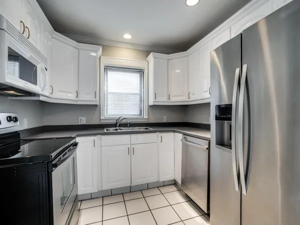 a kitchen with granite countertop a refrigerator sink and white cabinets