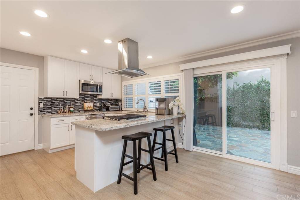 484 Traverse Drive Costa Mesa, CA 92626 - Photo 5 of 17 a kitchen with stainless steel appliances kitchen island granite countertop a stove a sink a refrigerator white cabinets and wooden floor