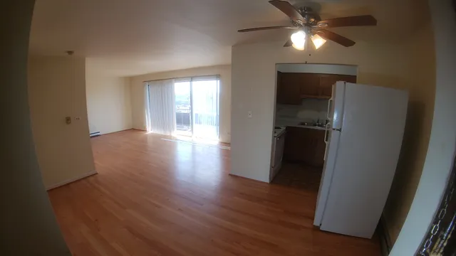 an empty room with wooden floor closet and windows