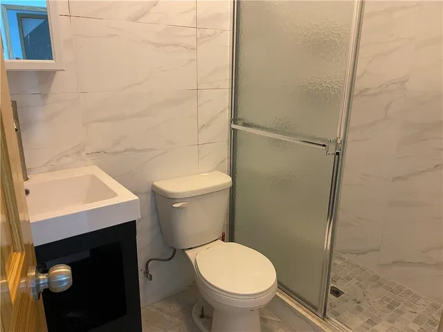 a white toilet sitting next to a shower