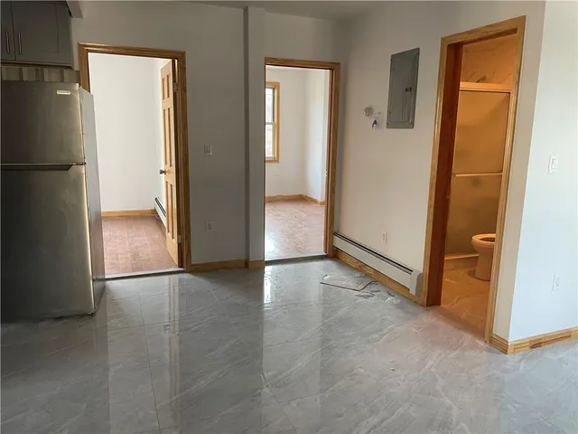 an empty room with wooden floor and a refrigerator