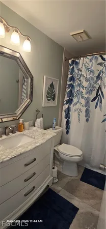 a bathroom with a granite countertop sink mirror vanity and toilet