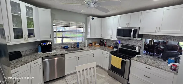 a kitchen with granite countertop a sink appliances cabinets and a counter top space