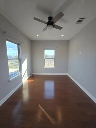 a view of an empty room with a window and wooden floor