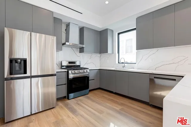 a kitchen with stainless steel appliances a sink a microwave a stove and white cabinets
