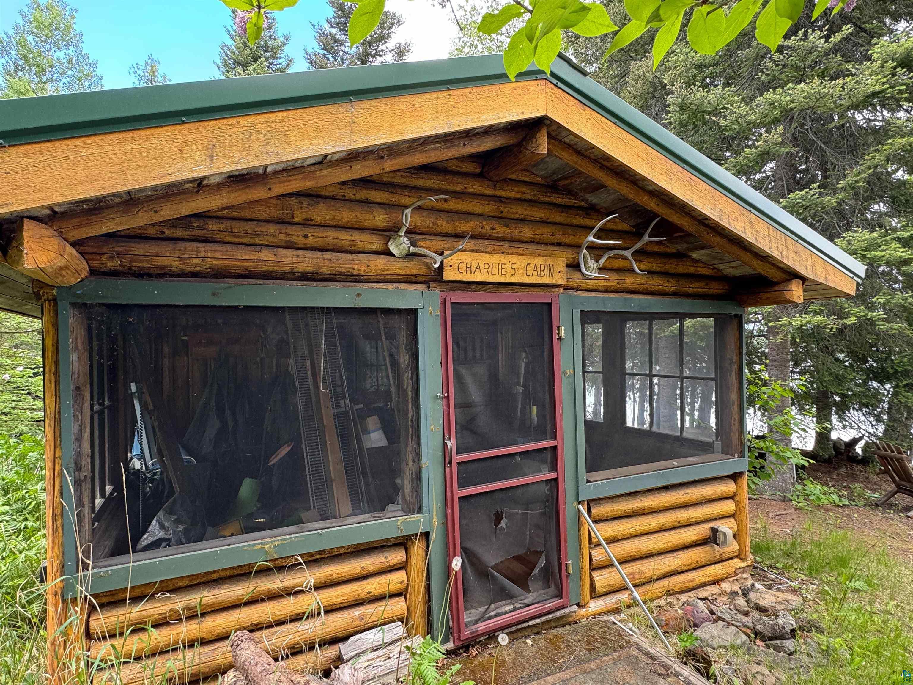 465 South Gunflint Lake Road Grand Marais, MN 55604 - Photo 11 of 46 Log cabin exterior with a green metal roof, screened windows, and a screened door