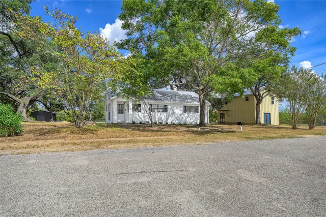 a front view of a house with a yard and a large tree