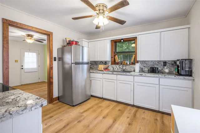 a kitchen with a refrigerator a stove cabinets and wooden floor