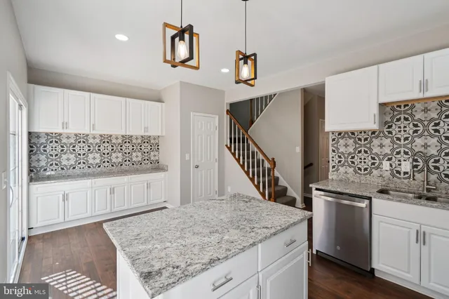 a kitchen with stainless steel appliances kitchen island granite countertop a stove and white cabinets with wooden floor