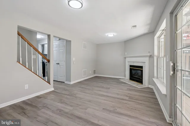 a view of an empty room with wooden floor fireplace and a window