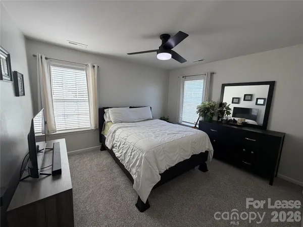 a bedroom with a bed and a flat tv screen on dresser