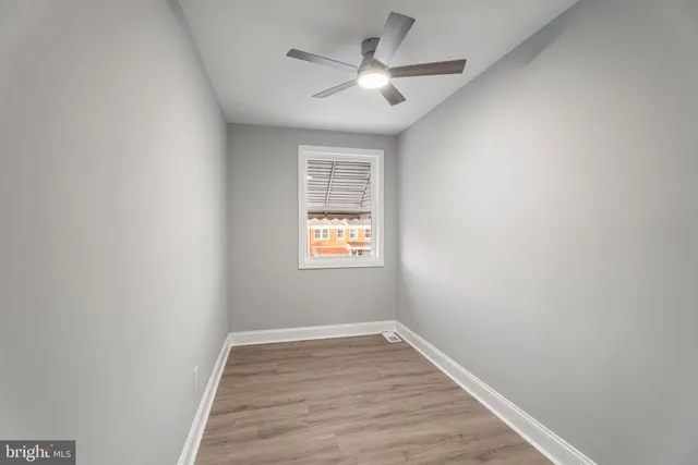 an empty room with wooden floor ceiling fan and windows