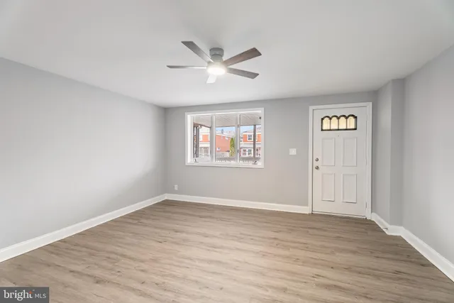 an empty room with wooden floor and a ceiling fan