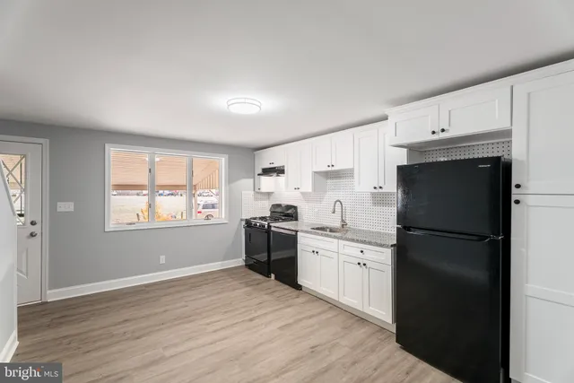 a view of an empty room with wooden floor and stairs