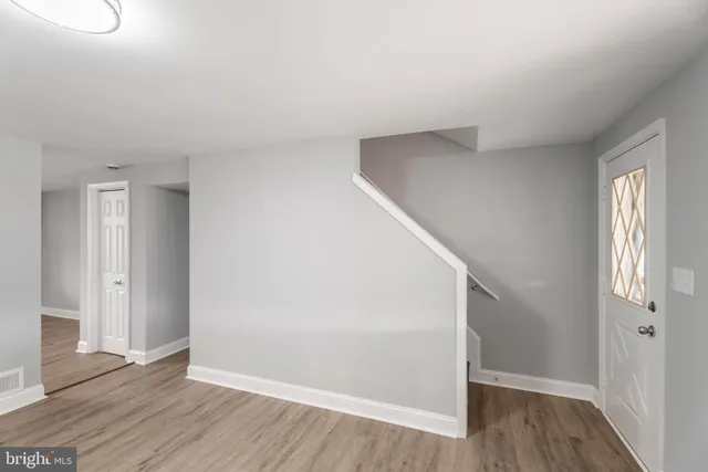 an empty room with wooden floor ceiling fan and windows