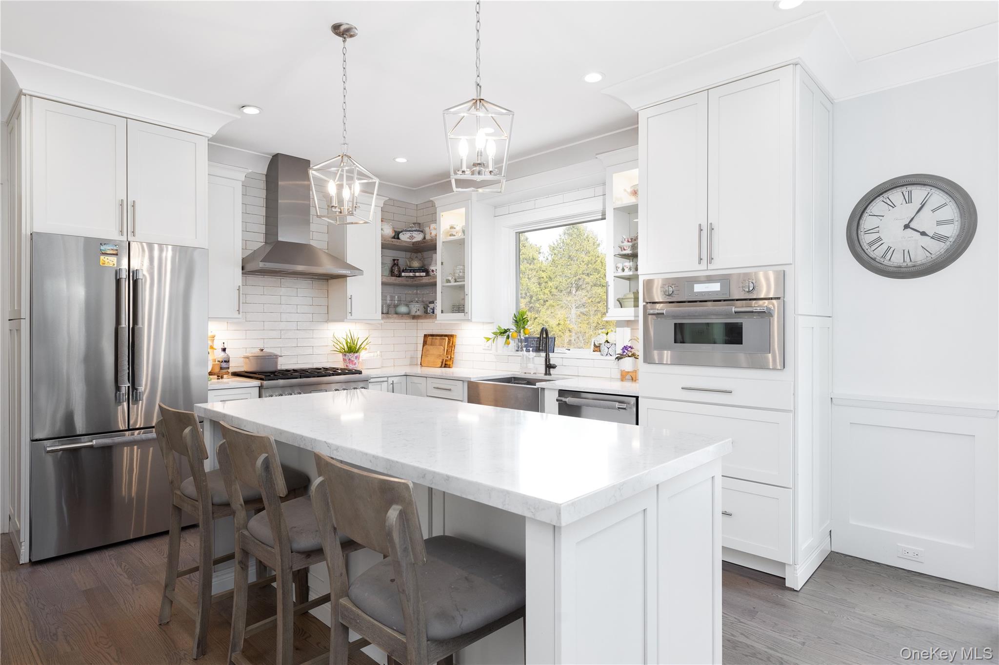 50 North Quarter Road Westhampton, NY 11977 - Photo 5 of 8 Kitchen with stainless steel appliances, a breakfast bar, pendant lighting, wall chimney range hood, and light stone countertops