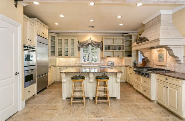 a kitchen with stainless steel appliances granite countertop a stove top oven island a table and chairs