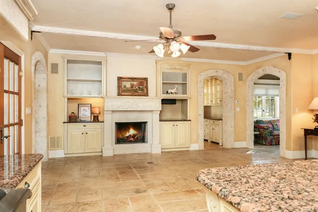 a view of a livingroom with a fireplace a chandelier and windows