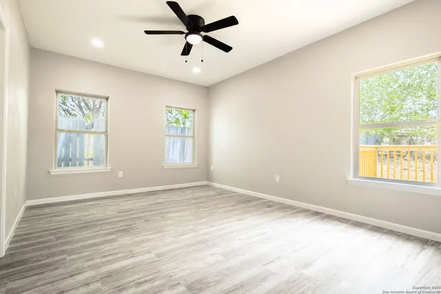 a view of empty room with wooden floor and fan