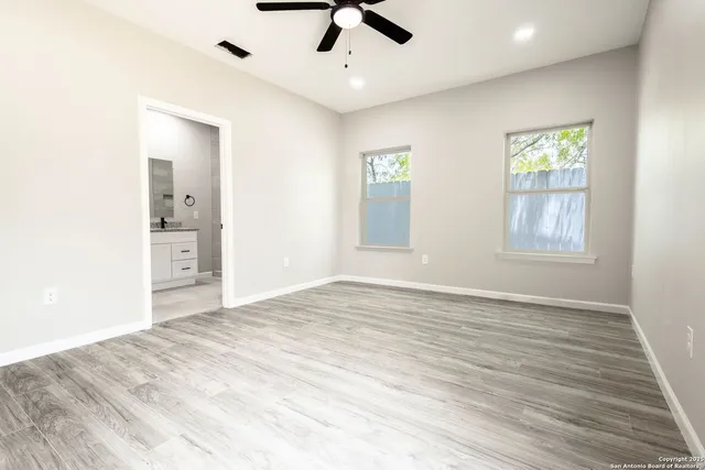 a view of an empty room with window and wooden floor