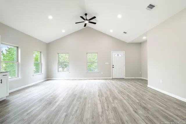 a view of an empty room with a window and wooden floor