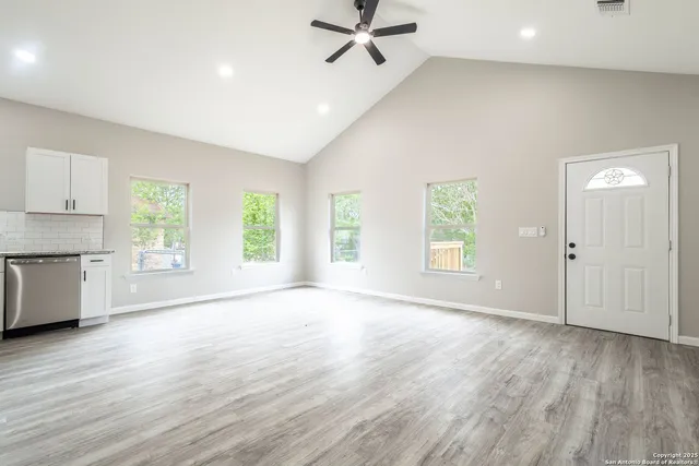 a view of an empty room with a window and wooden floor