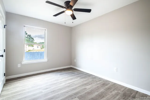 a view of an empty room with wooden floor and a window