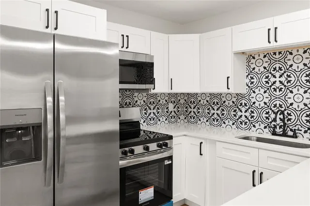 a kitchen with granite countertop white cabinets and stainless steel appliances