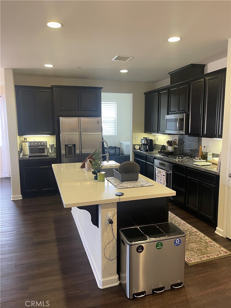 29192 Jacaranda Lake Elsinore, CA 92530 - Photo 4 of 7 a kitchen with stainless steel appliances kitchen island granite countertop a stove a sink and a refrigerator