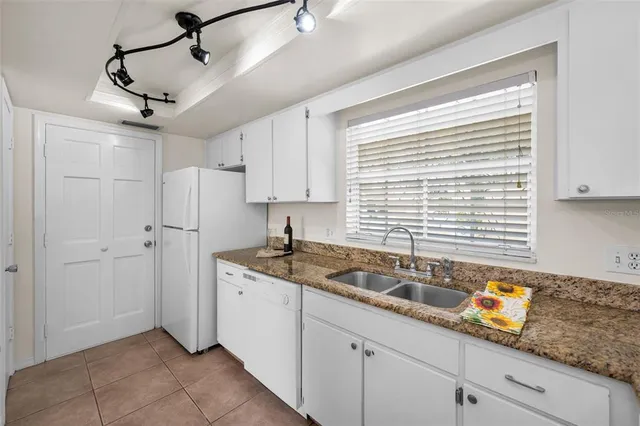 a kitchen with granite countertop white cabinets and white appliances