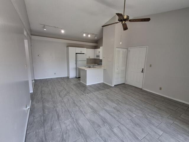 701 Lyons Road, Unit 13208 Coconut Creek, FL 33063 - Photo 4 of 31 an empty room with wooden floor a ceiling fan and kitchen view