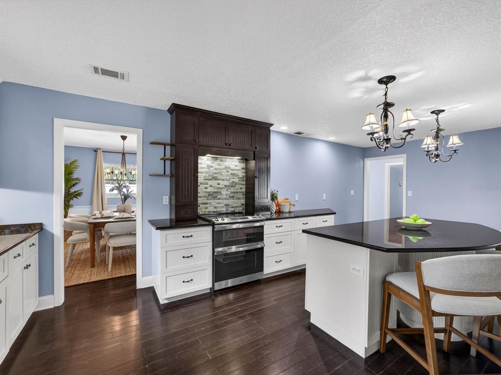 333 Cornwall Road Winter Park, FL 32792 - Photo 4 of 32 a kitchen with stainless steel appliances kitchen island granite countertop a stove a sink dishwasher a dining table and chairs with wooden floor
