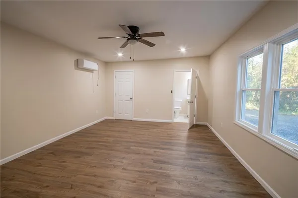 a view of an empty room with a window and wooden floor