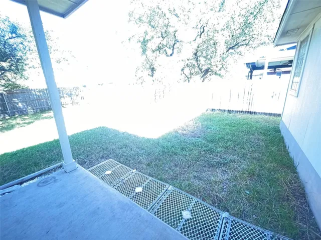 a view of a backyard with large trees and wooden fence