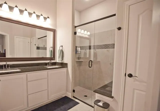 a bathroom with a double vanity sink mirror and shower