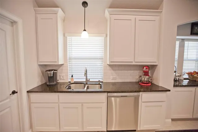 a kitchen with granite countertop white cabinets and a sink