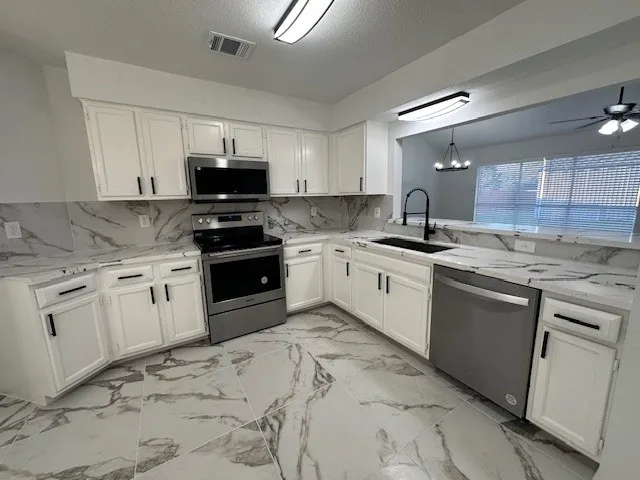 a kitchen with granite countertop a sink a stove and cabinets