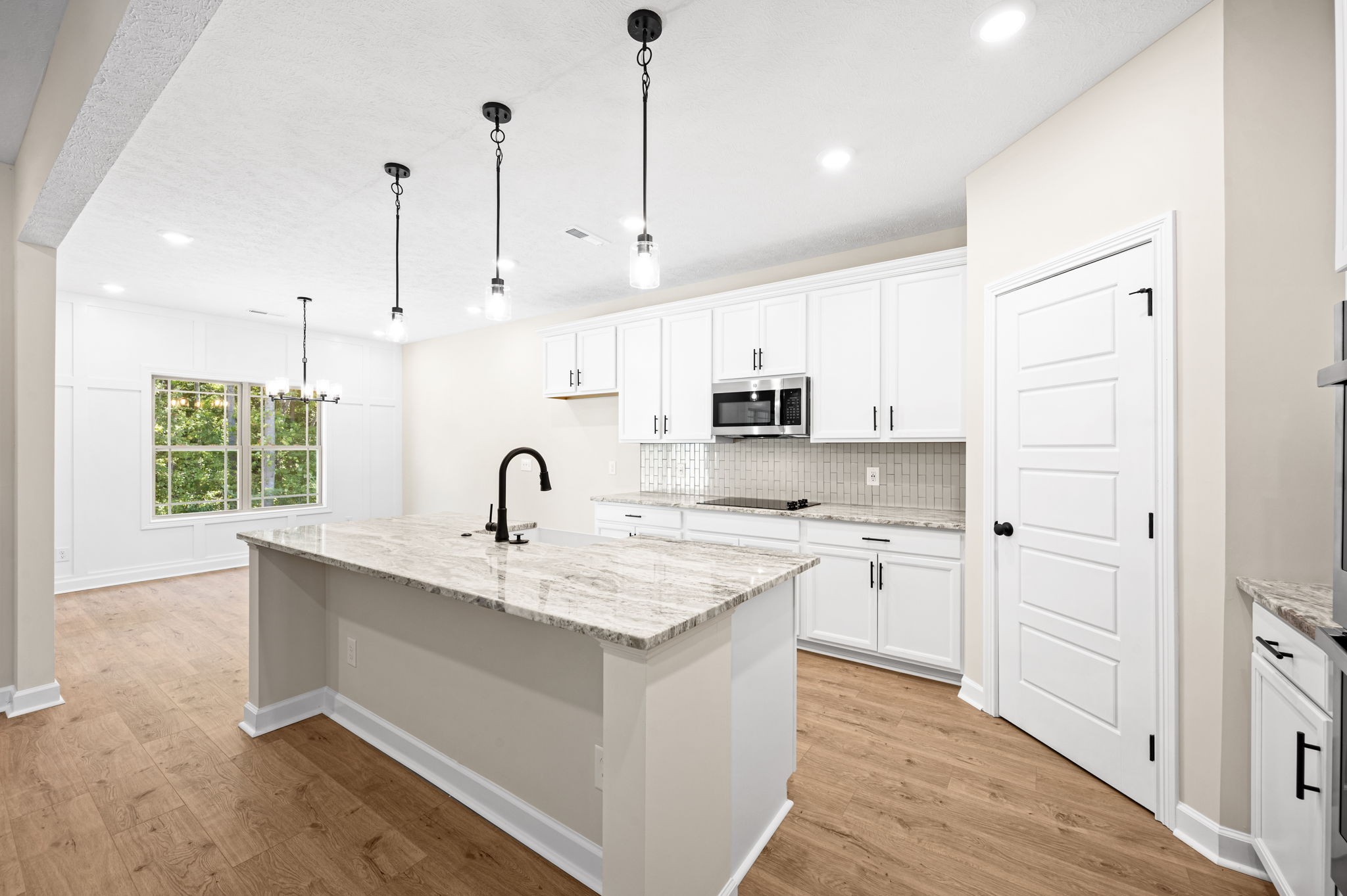 1749 Powell Road Clarksville, TN 37043 - Photo 9 of 50 a view of a kitchen with kitchen island a sink wooden floor and white cabinets