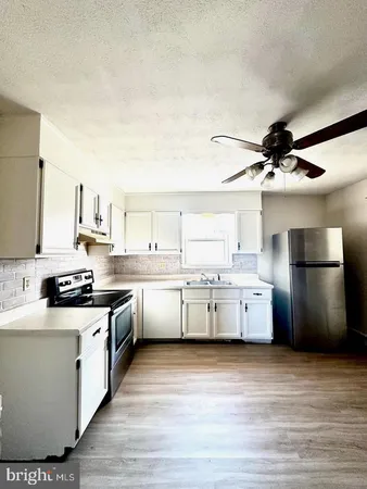 a kitchen with stainless steel appliances a sink cabinets and wooden floor