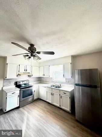 a kitchen with stainless steel appliances granite countertop a sink a stove a refrigerator and island with wooden floor