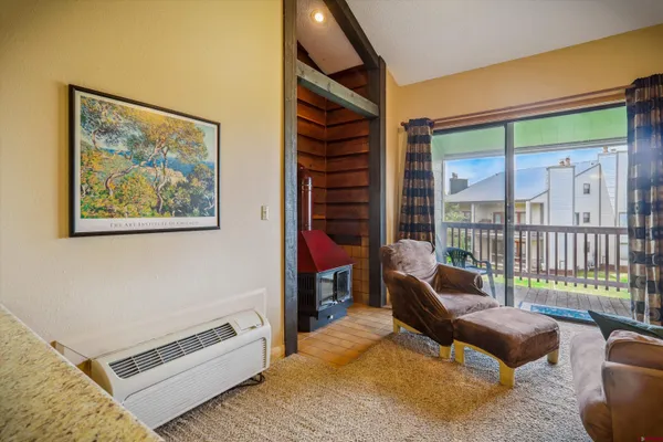 a living room with furniture a flat screen tv and a floor to ceiling window
