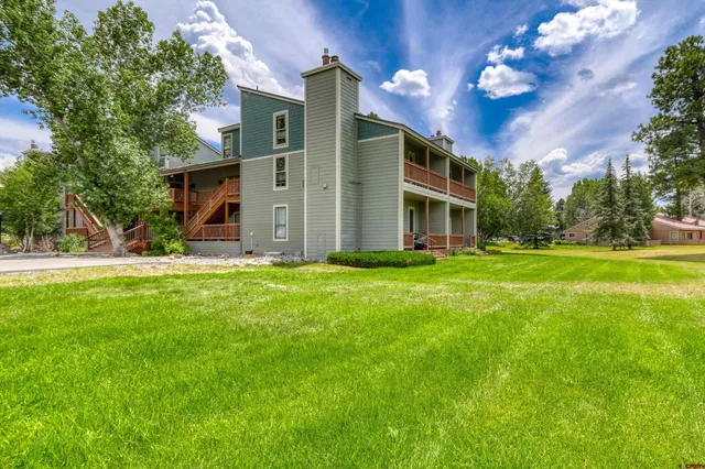 a view of a house with a big yard and large trees