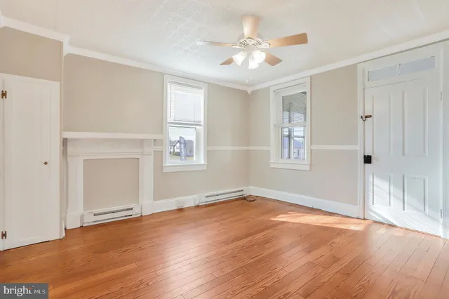 an empty room with wooden floor chandelier and windows